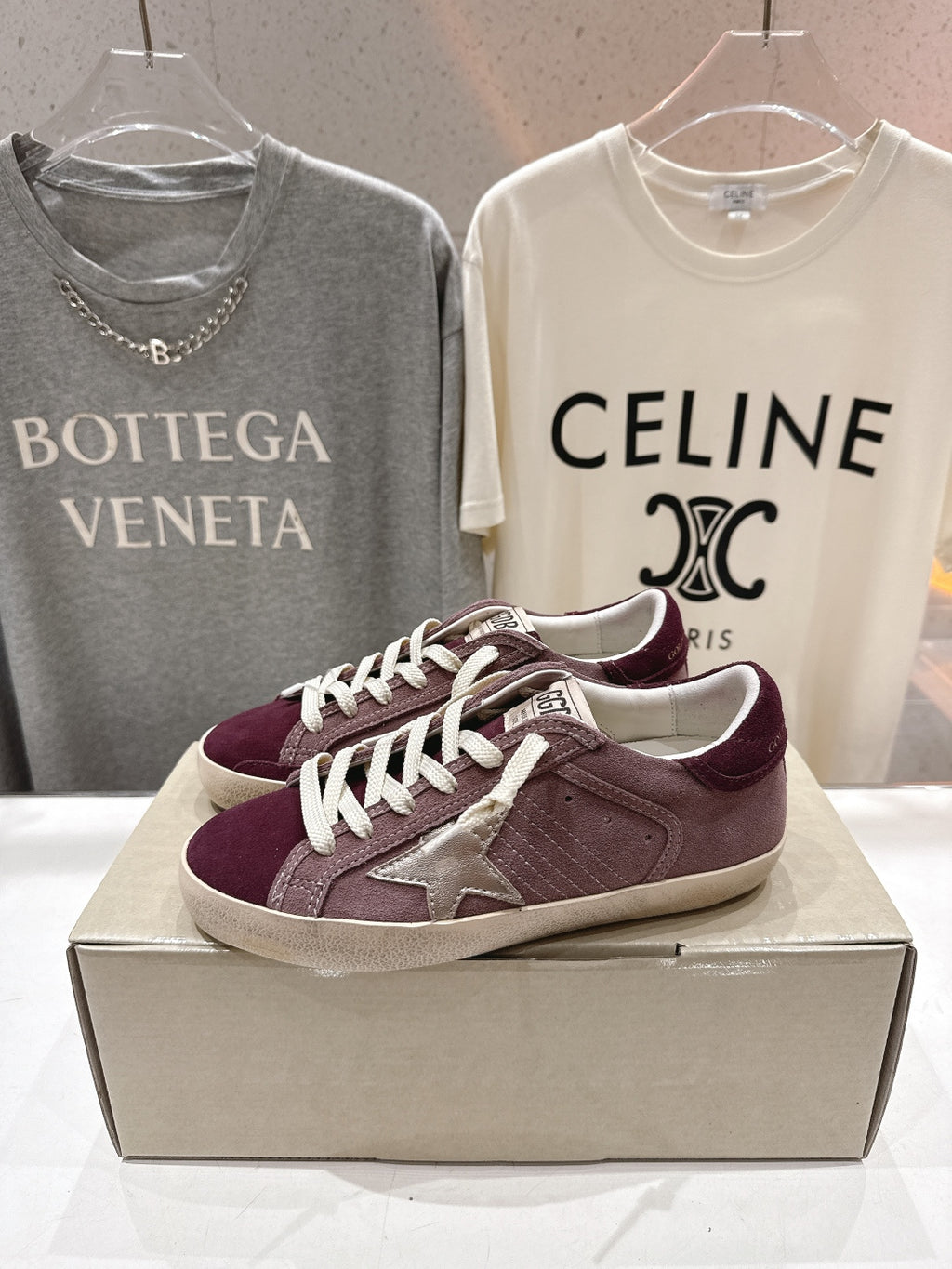 Maroon suede sneakers with white laces and star appliqué, side angle on box.