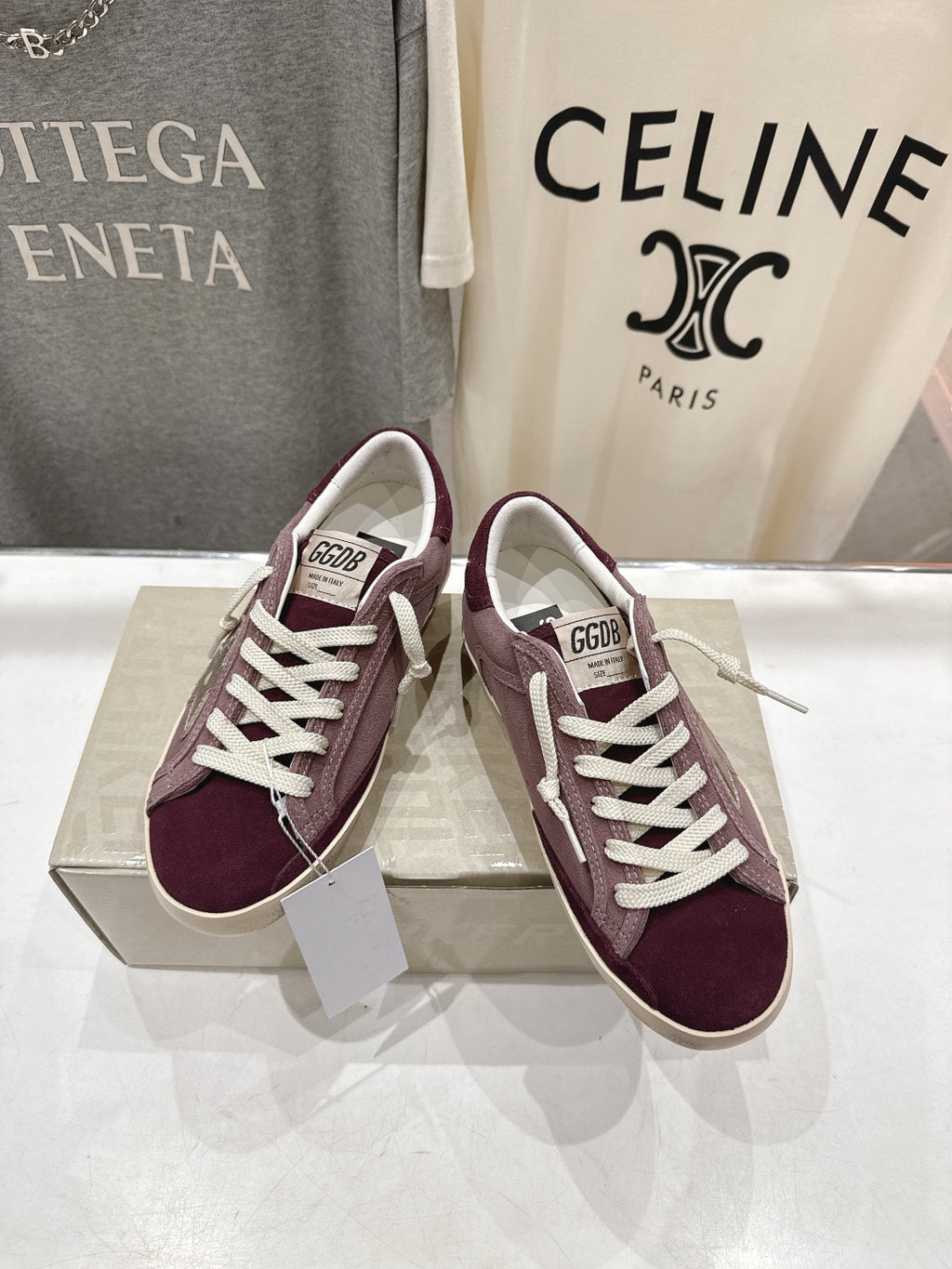 Maroon suede sneakers with white laces, side view, beige sole.