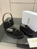 Black suede slip-on loafers with gold buckle trim and chunky platform sole