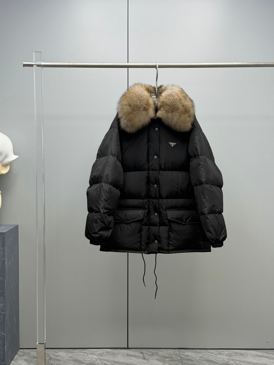 Long black puffer jacket with tan fur hood trim and buttoned front