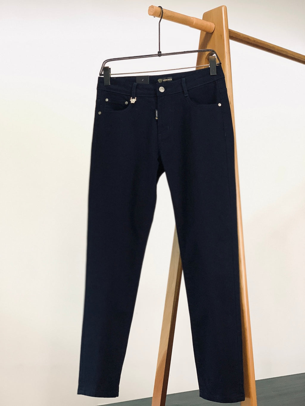 Navy denim trousers on hanger with front pockets and button waist