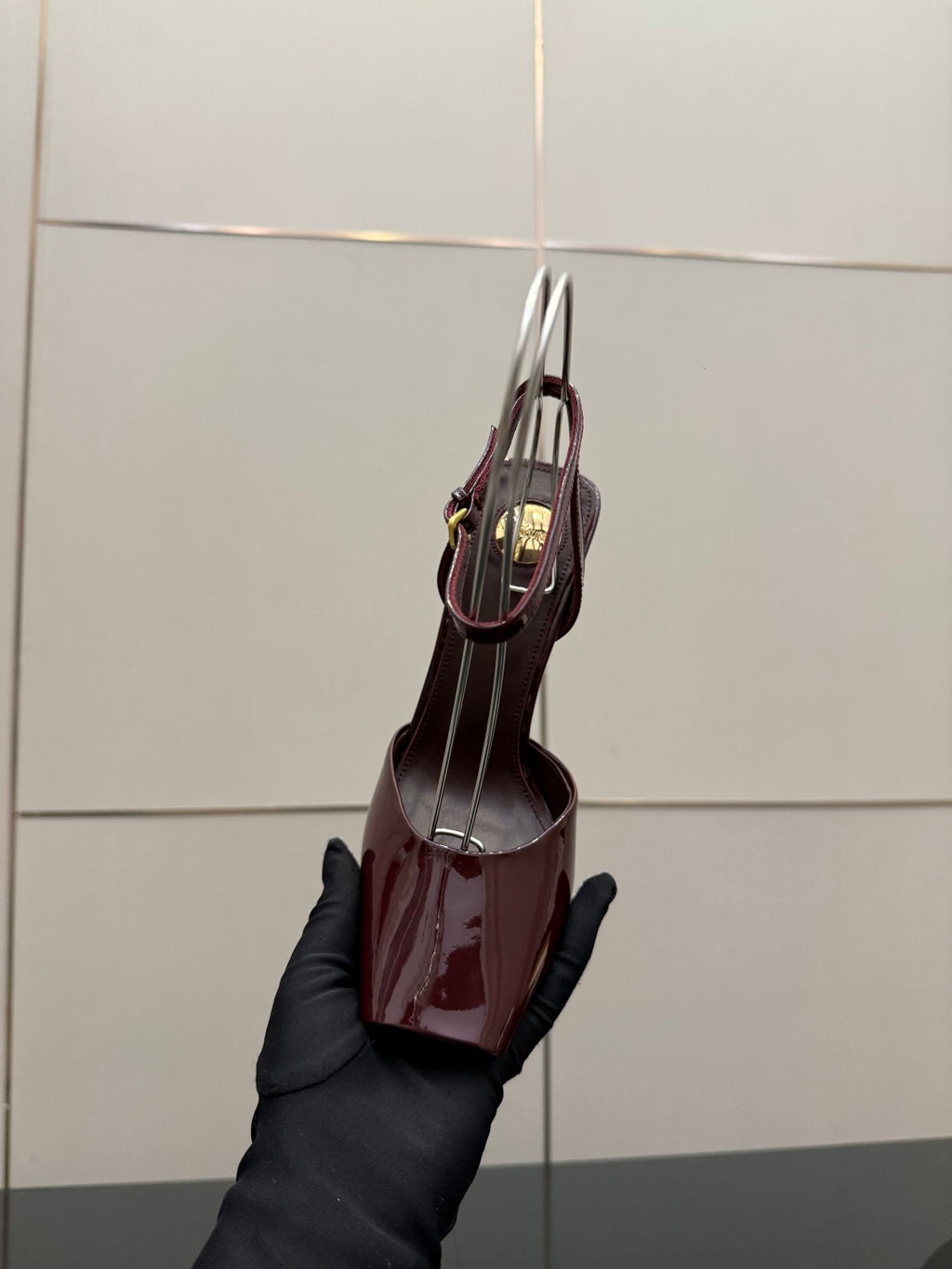 Burgundy patent sandal held up, open toe and ankle strap