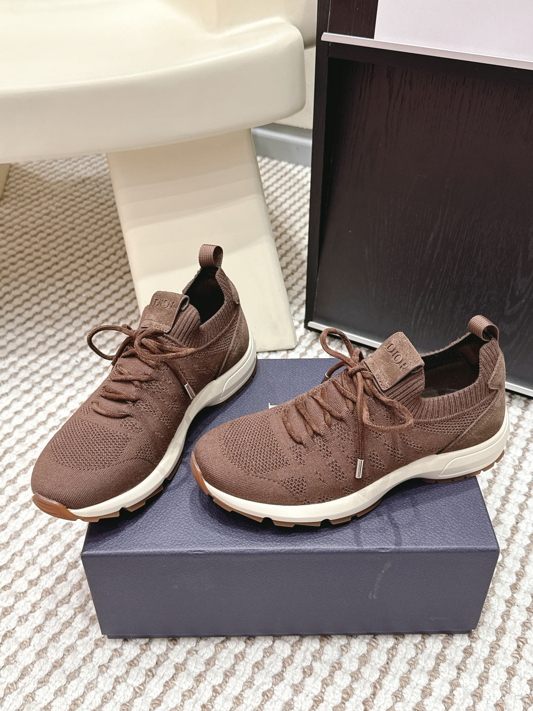 Pair of brown unisex knit lace-up sneakers on a shoe box