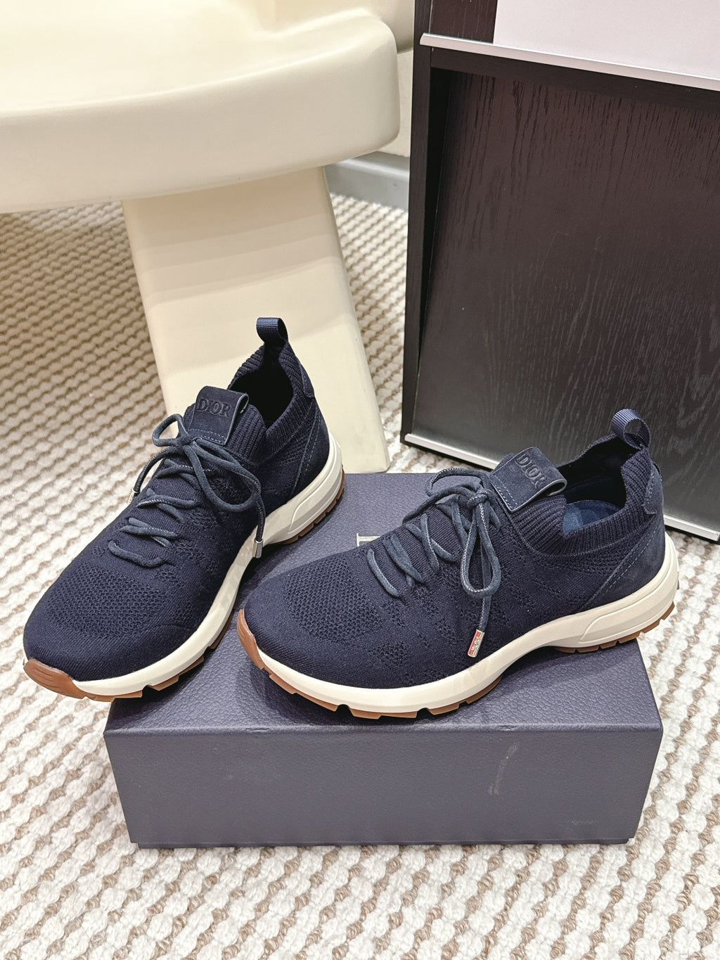 Navy lace-up knit sneakers on a box with thick white sole and Dior tongue patch