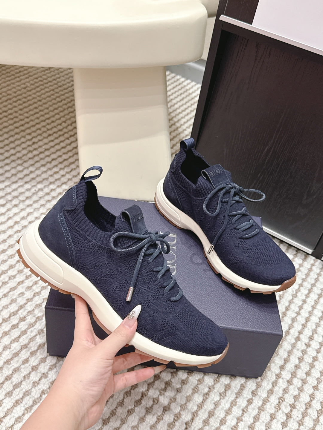 Navy knit sneakers with lace-up front and white sole, shown pair on gift box