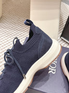 Navy knit sneakers with sock-like collar, lace-up cords, and white rubber sole