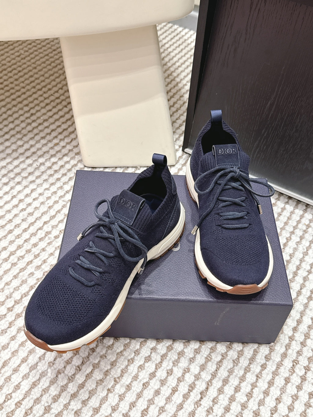 Navy knit sneakers with lace-up design, white sole, and Dior logo on tongue