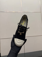 Chanel women’s lace-up sneaker held in hand, dark upper with white toe panel