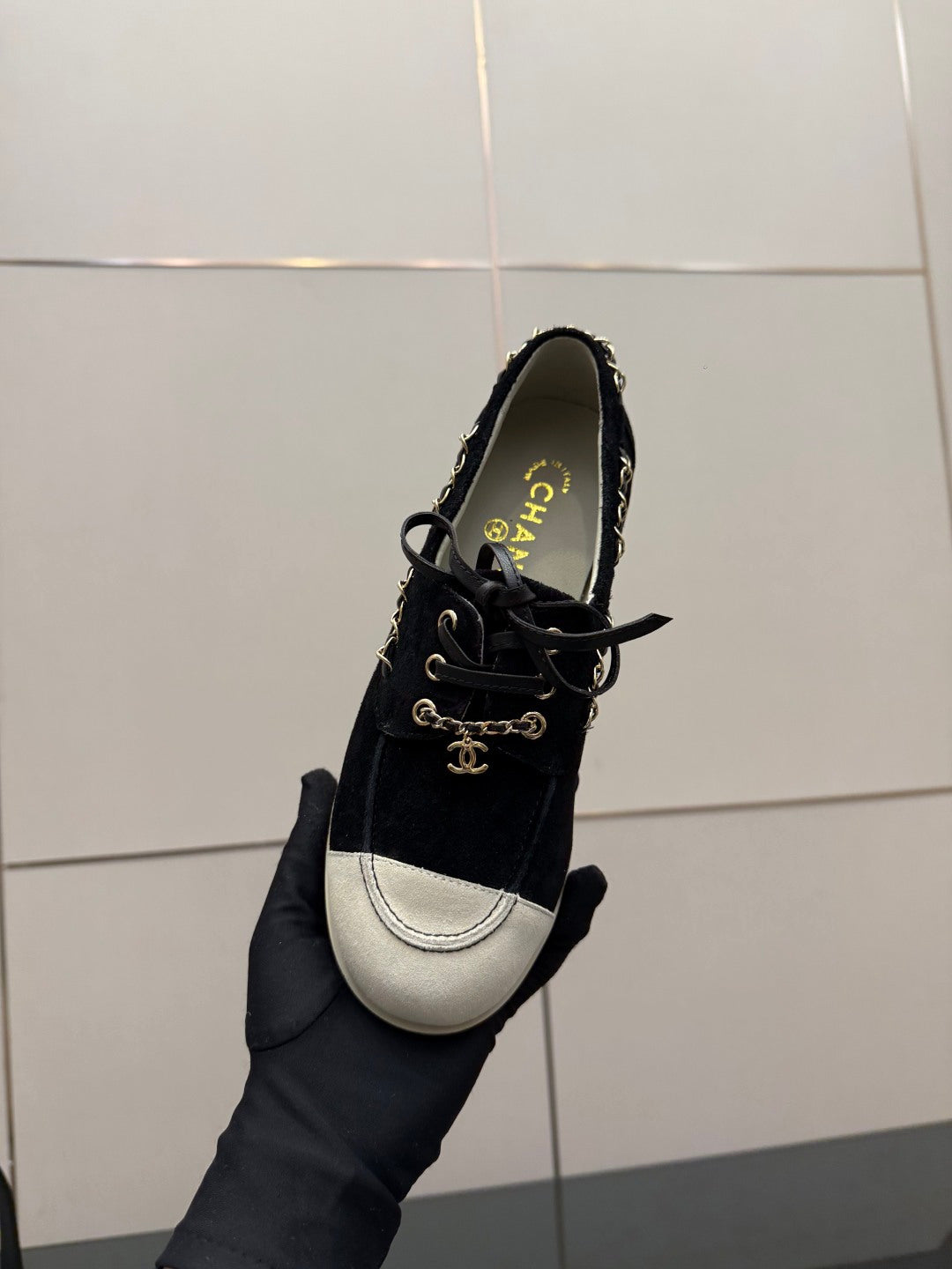 Chanel women’s lace-up sneaker held in hand, dark upper with white toe panel