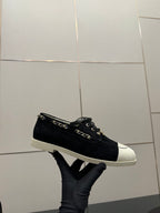 Chanel women’s low-top sneakers with dark upper and white toe cap, chain detail
