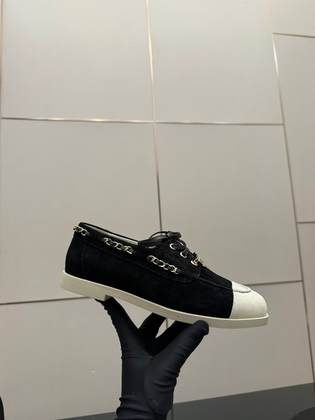 Chanel women’s low-top sneakers with dark upper and white toe cap, chain detail