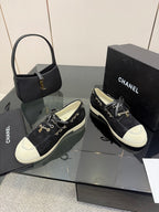 Chanel women’s lace-up sneakers pair, dark fabric with white toe caps and chain detail