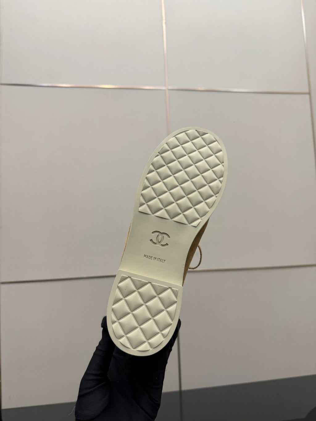 Ladies tan sneaker outsole view, quilted white tread with small logo mark