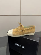 Ladies tan suede low-top sneaker on box, lace-up style with white toe caps