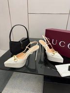 Pair of white Gucci slingback heels with gold buckle and stiletto heel