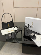 Black heeled sandals with ankle buckle straps and Dior logo on the band.