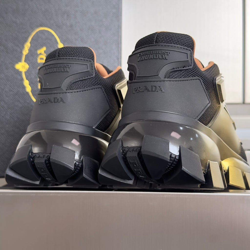 Prada unisex sneakers rear view with black uppers and metallic gold toe highlights