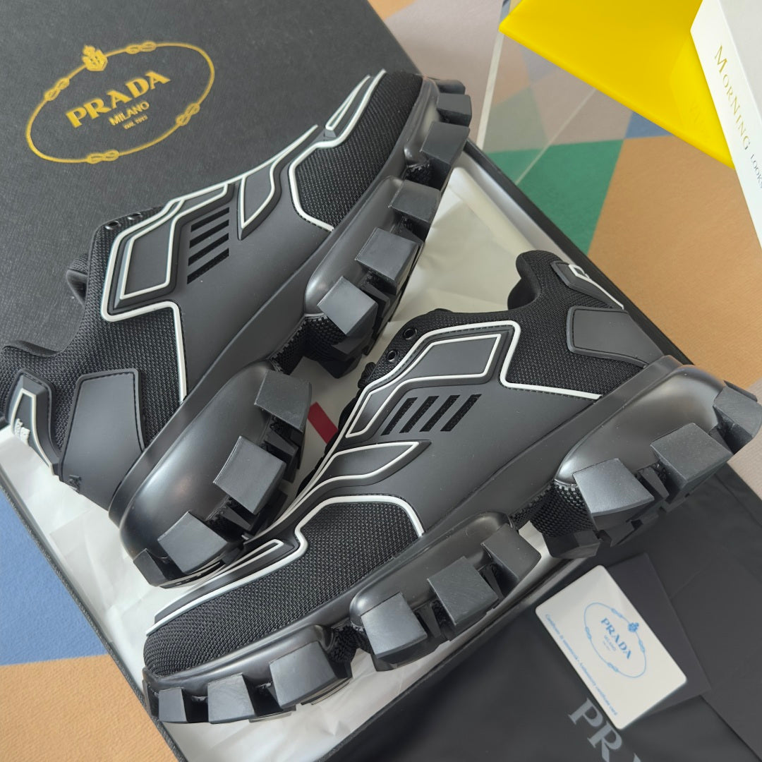 Prada unisex sneaker outsole view, black tread blocks with gray sidewall panels