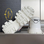 White sneaker outsoles with deep traction blocks and rear heel lettering