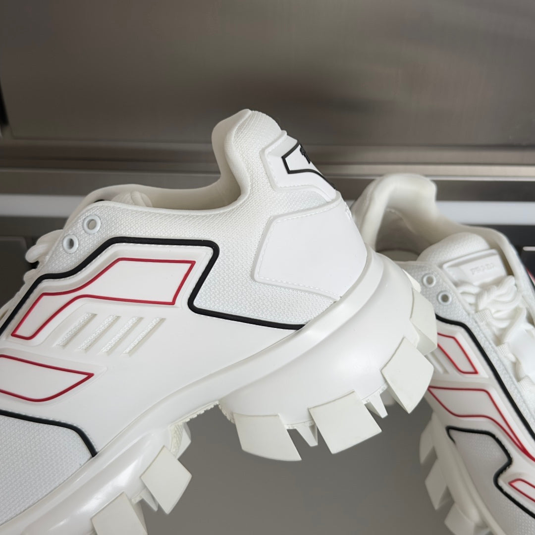 White sneakers close-up on side, red/black accents and chunky outsole blocks