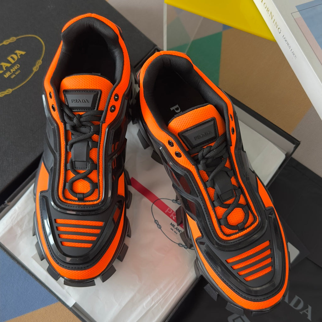 Unisex chunky sneakers close-up, black laces and orange trim with molded side logo