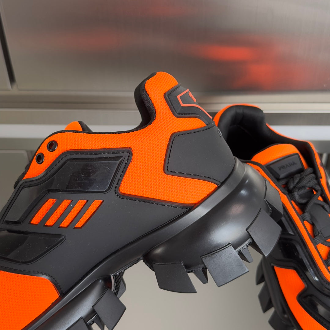 Prada unisex sneaker, orange and black, close-up of high-top and tread sole.