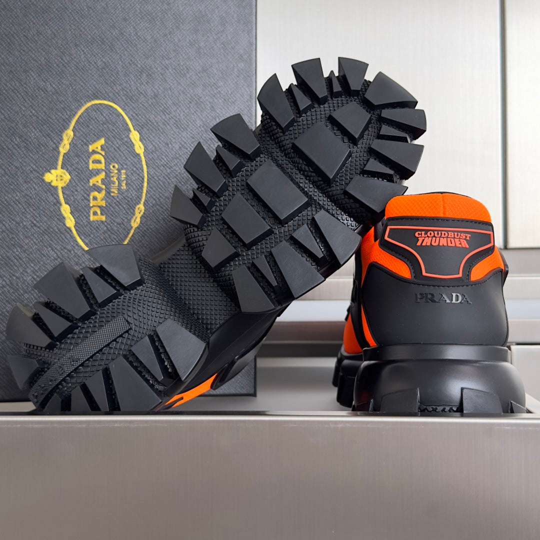 Prada unisex sneaker, black outsole tread detail with orange heel accents.