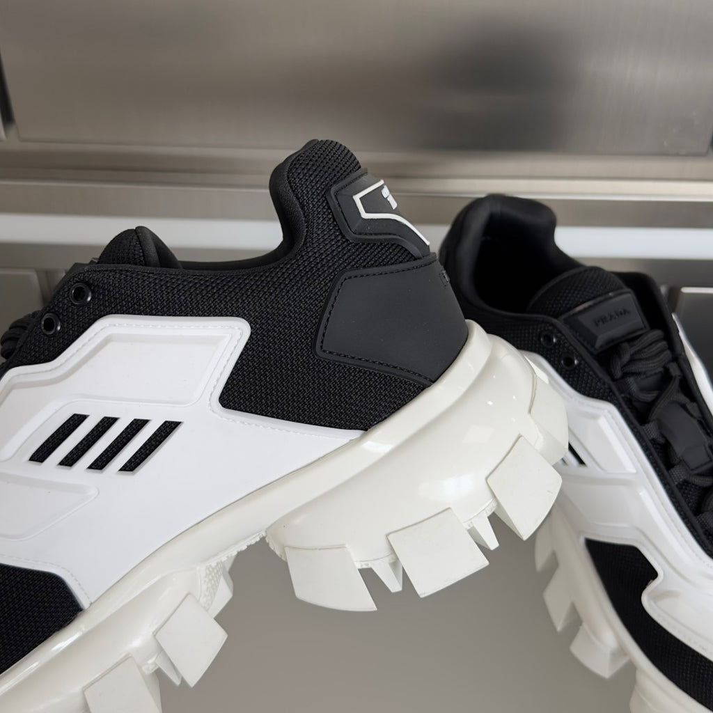 Black knit sneaker with white trim, lace-up eyelets, and chunky white lug sole