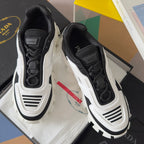 Prada unisex sneakers showing side panels and lace-up front, black uppers with white soles