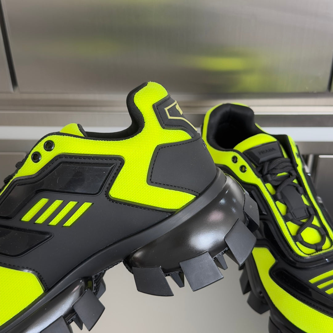 Neon green and black Prada sneaker with lace eyelets, hook detail, and rugged tread