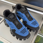 Pair of blue and black chunky sneakers with lace-up design and rugged spiked outsole