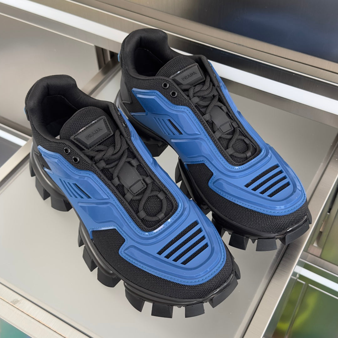 Pair of blue and black chunky sneakers with lace-up design and rugged spiked outsole