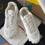 White lace-up sneakers with textured panels and red detail tag