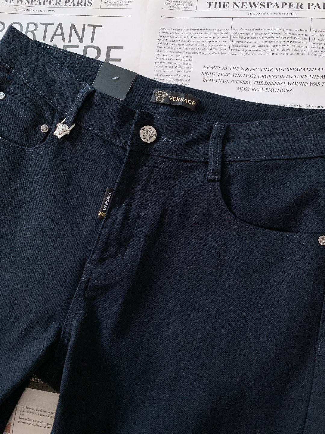 Dark denim jeans with Versace tag, rivet detailing, and button fly