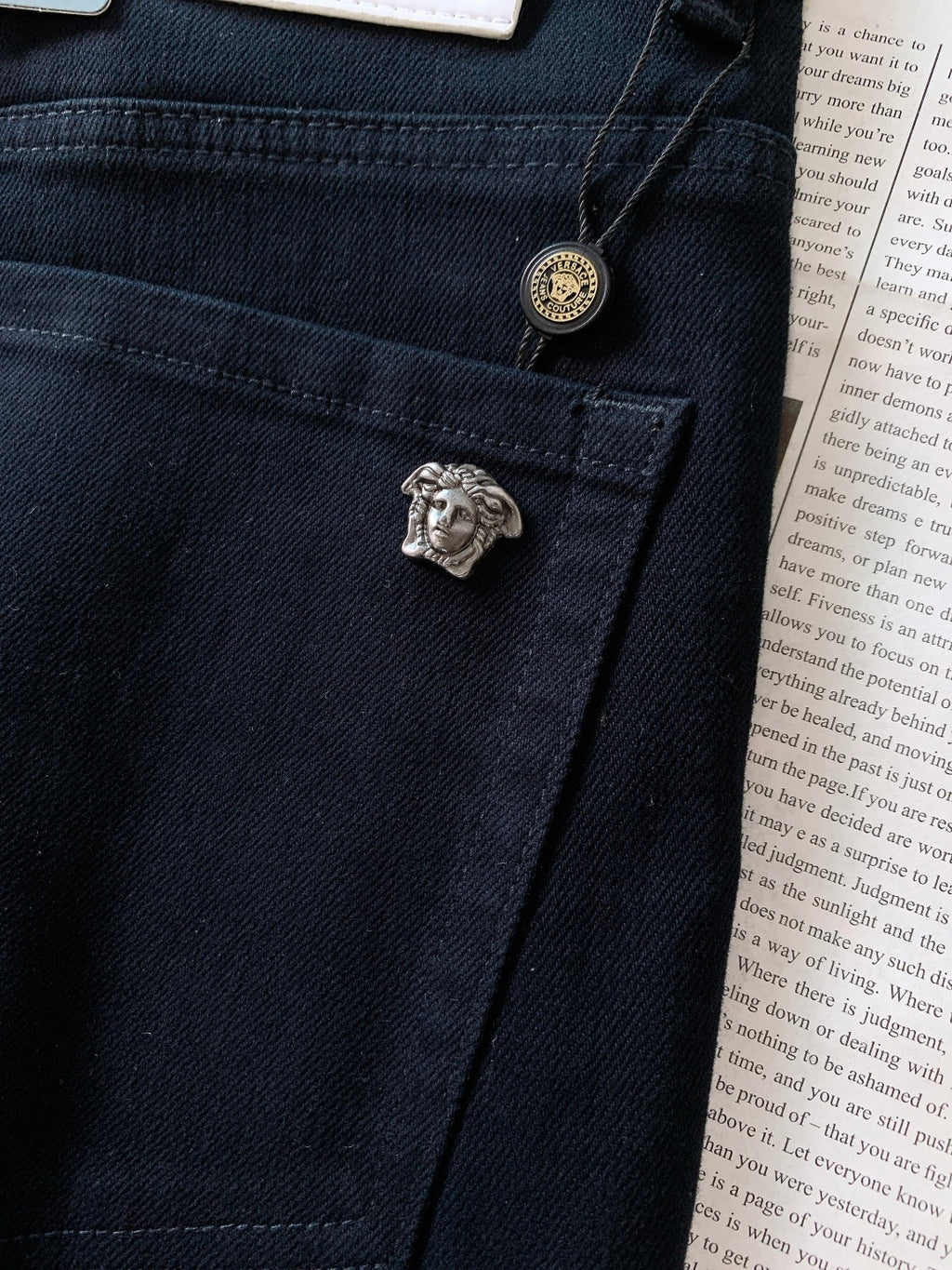 Dark denim jeans with small lion emblem button and stitched seam detail