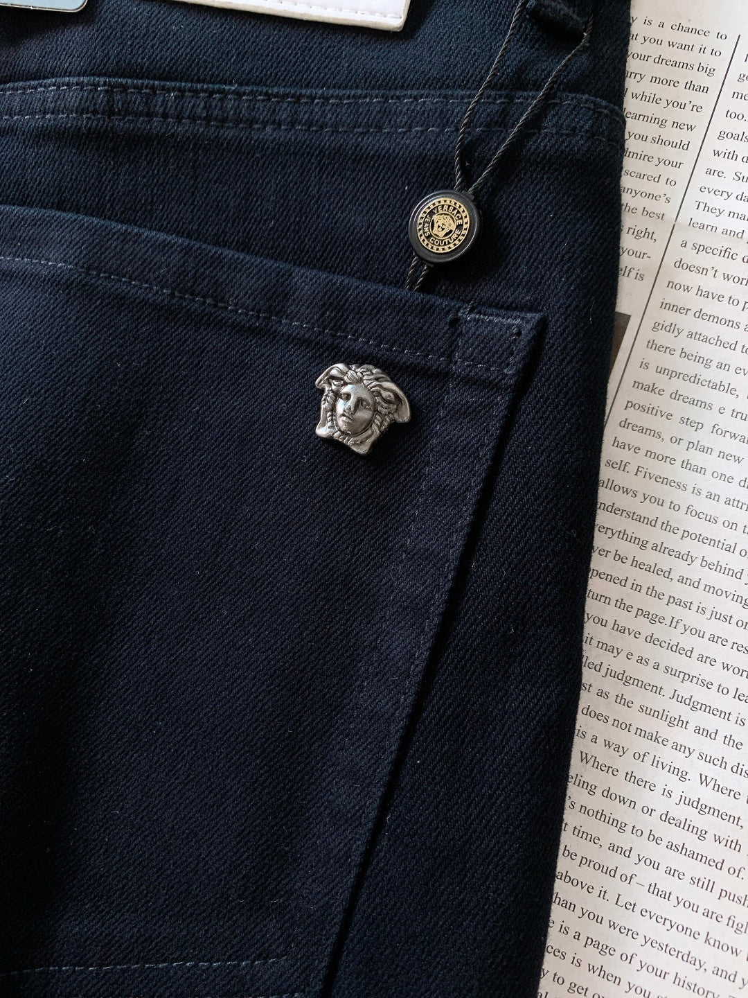 Dark denim jeans with small lion emblem button and stitched seam detail