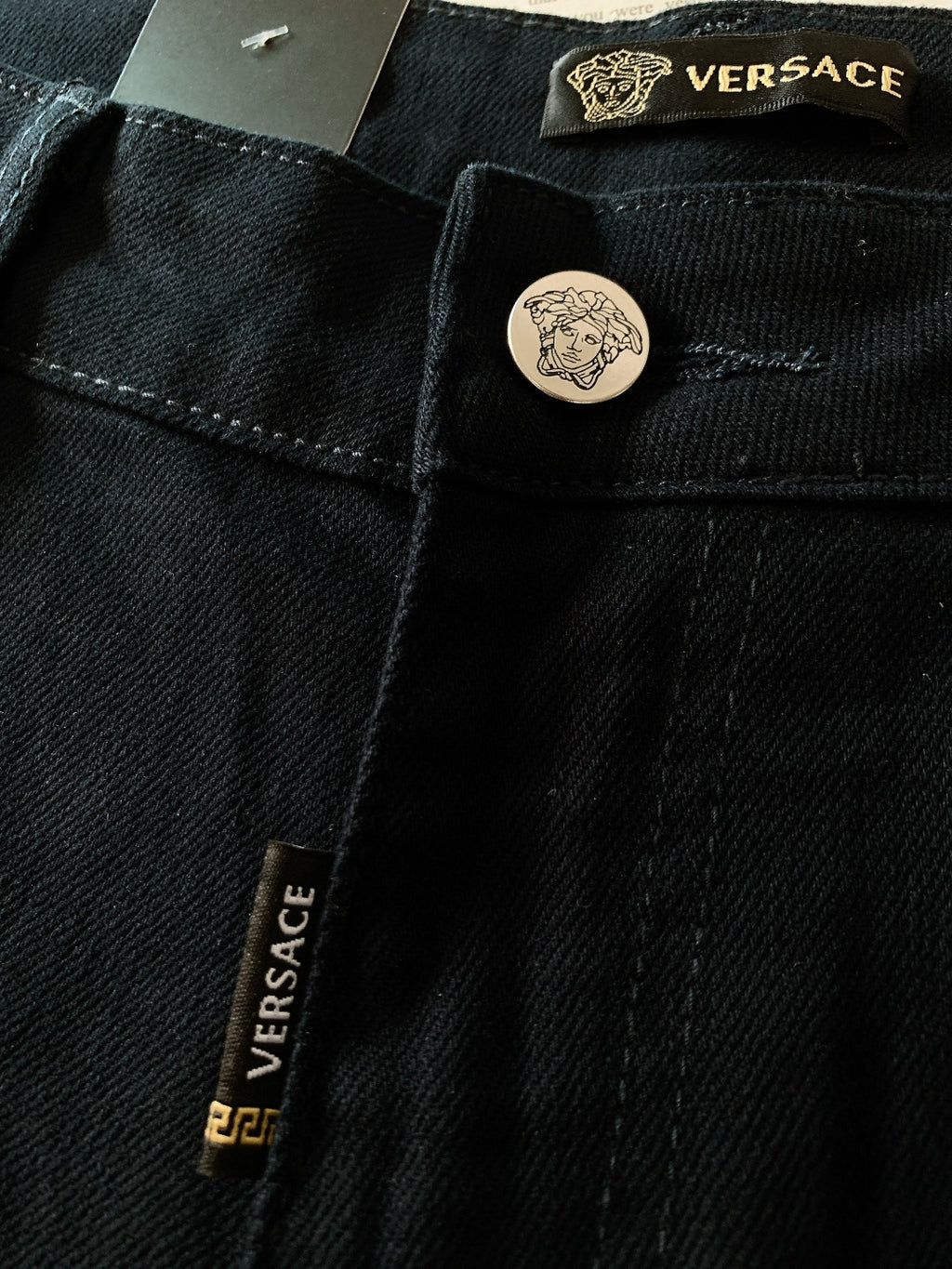 Black denim jeans with Versace label and round engraved button