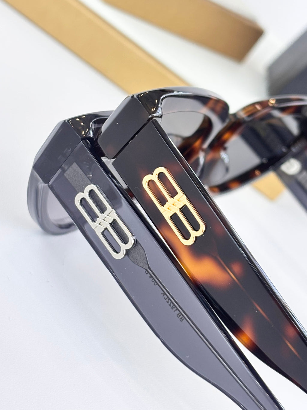 Gold B logo on dark temple of cat-eye sunglasses with mirrored lens