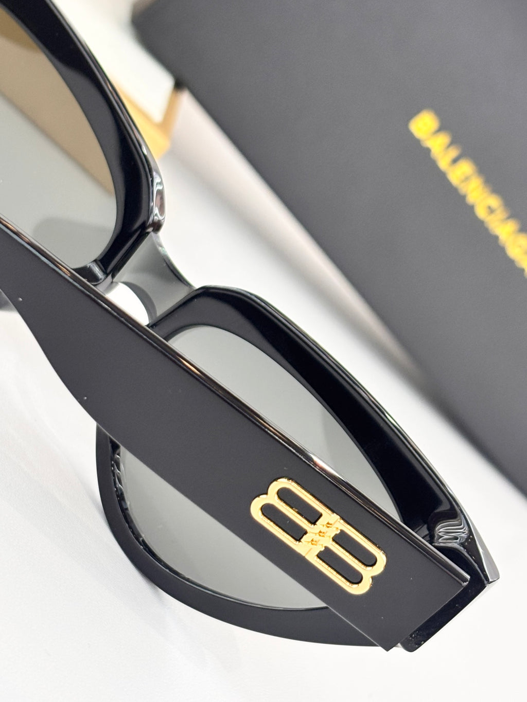 Gold B logo on black temple of cat-eye sunglasses with tinted lens