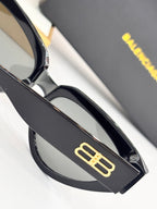Gold B logo on black temple of cat-eye sunglasses with tinted lens