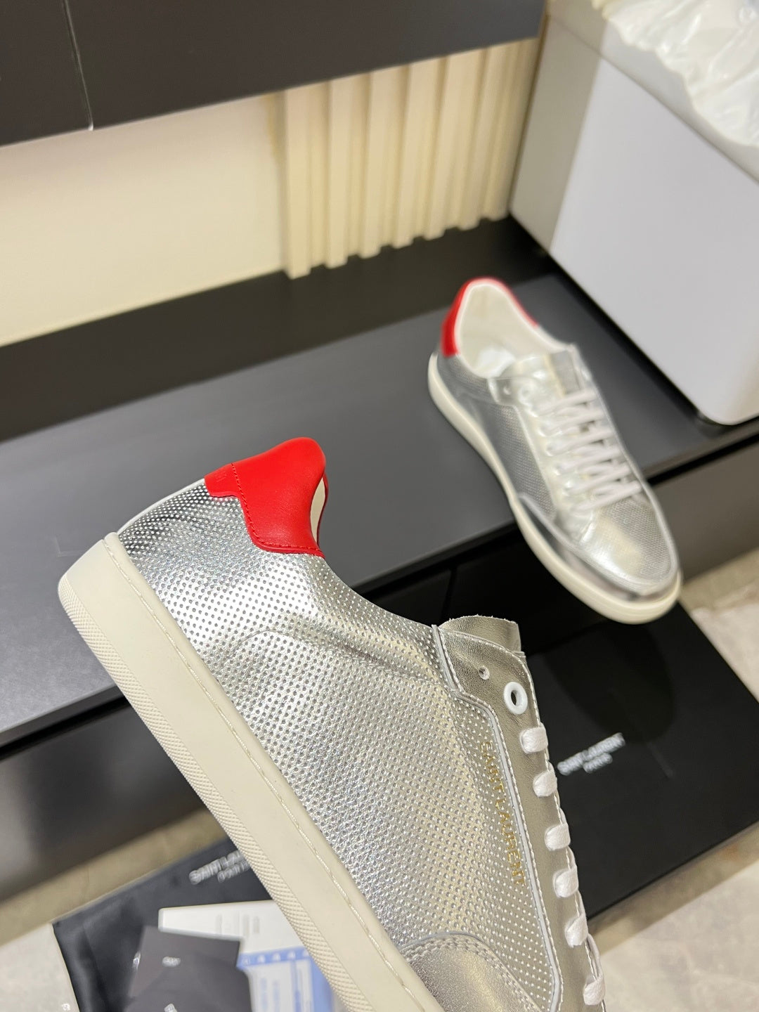 Unisex low-top sneakers side view, silver upper with red heel patch and white sole