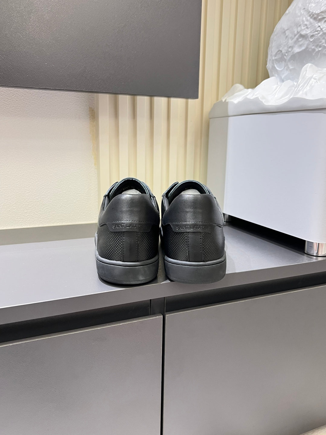 Dark gray low-top sneakers rear view on a shelf with lace-up fronts