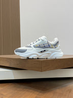 Chunky white low-top sneakers with light blue side panel and plaid strap detail