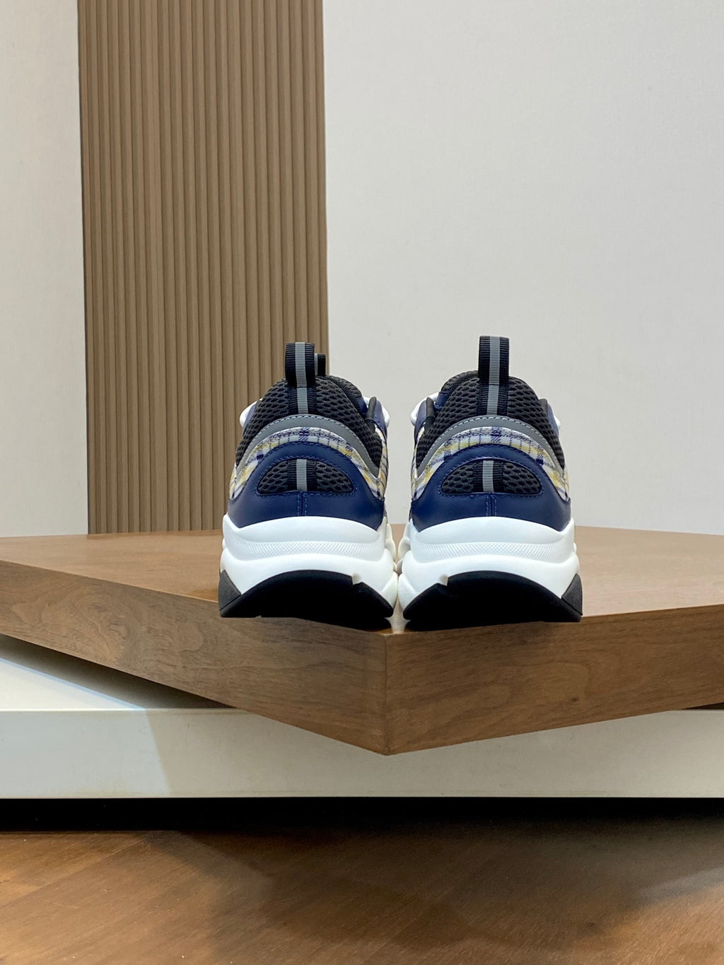 Dior unisex sneakers back view on shelf, navy heels with white sole and blue accents