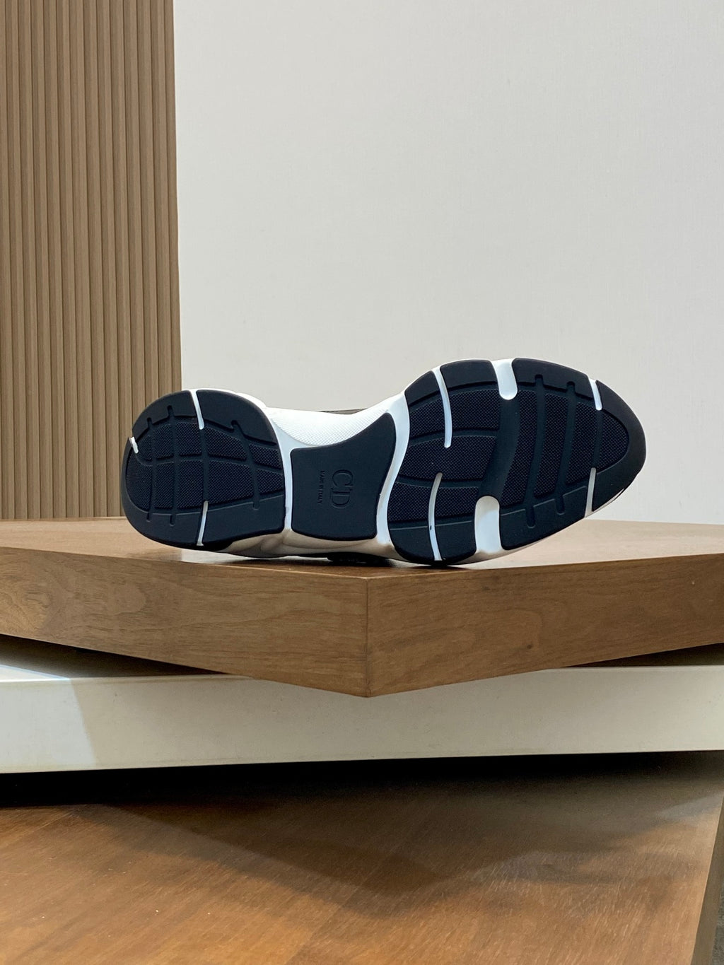 Outsole view of navy Dior sneakers, rubber tread with white midsole