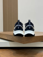 Back view of navy Dior sneakers with chunky white soles and heel pull tabs