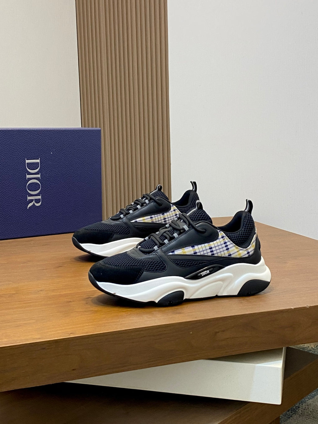 Dior unisex sneakers on display, navy knit upper with plaid side panel and white sole