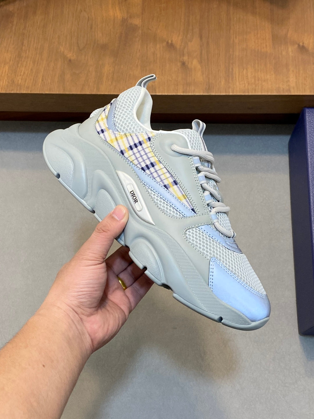 Light blue lace-up sneaker close-up with blue plaid stripe and textured sole