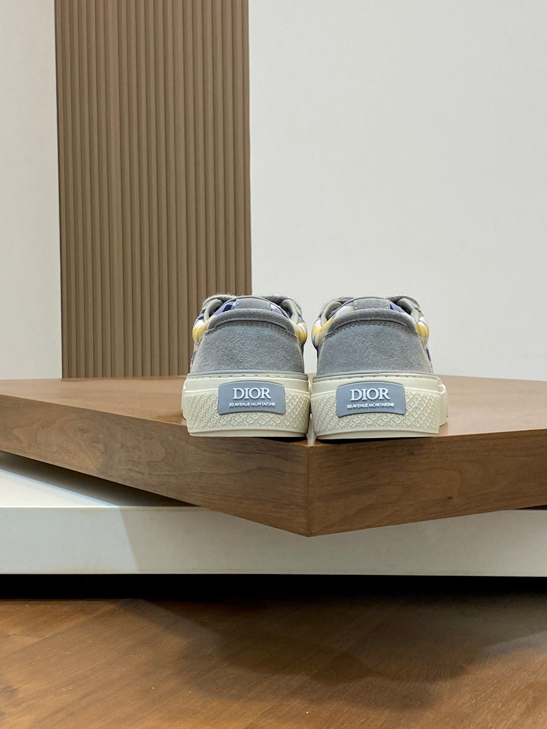Grey low-top Dior sneakers with rear heel branding and blue-yellow accents