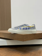 Grey low-top sneakers with blue-yellow plaid side and textured white sole